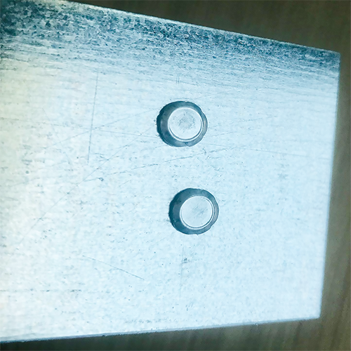 Two circular clinching impressions on a sheet metal component